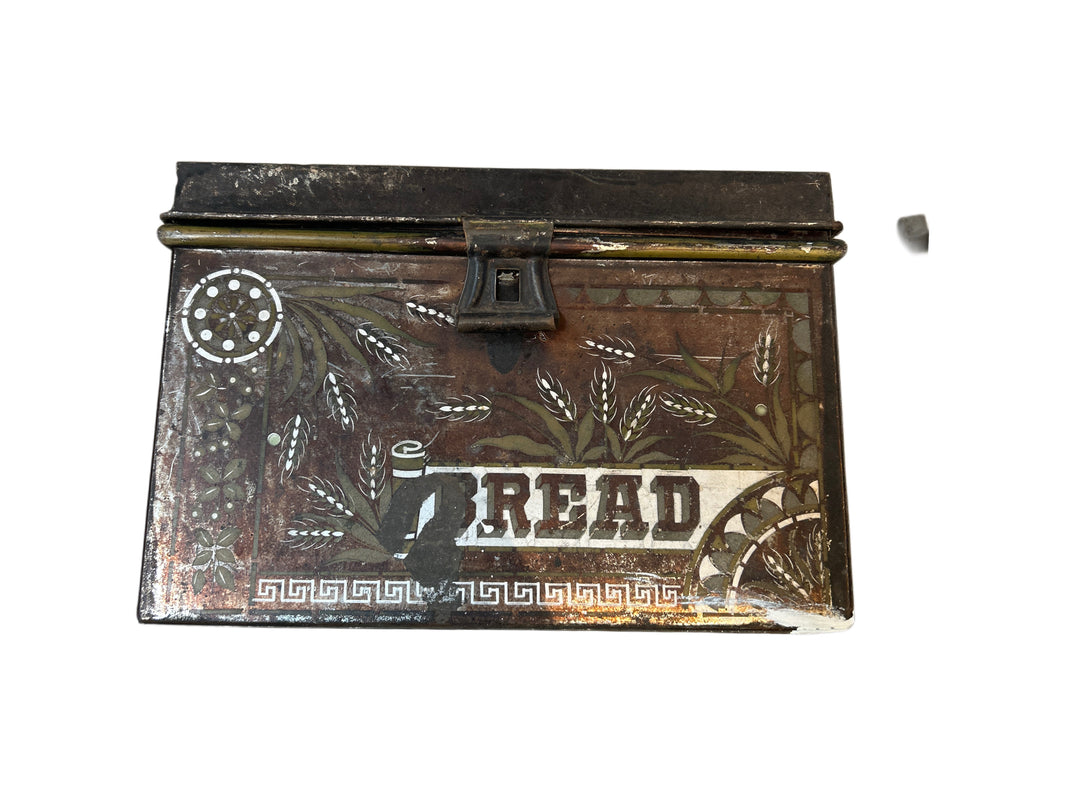 The Bread Box is a vintage metal container with a hinged lid, bold "BREAD" lettering, floral and wheat designs, a front lock, and includes a small detached metal piece.