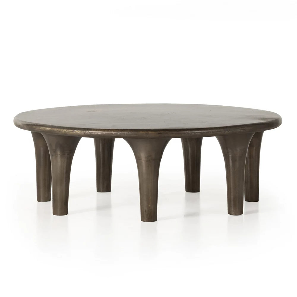 The Kelden Coffee Table is a round, dark brown piece with a smooth top and eight evenly spaced, tapered legs. Measuring 48 inches in diameter, this table features a sturdy modern design that makes it a stylish addition to your living room furniture collection. Shown on a white background.