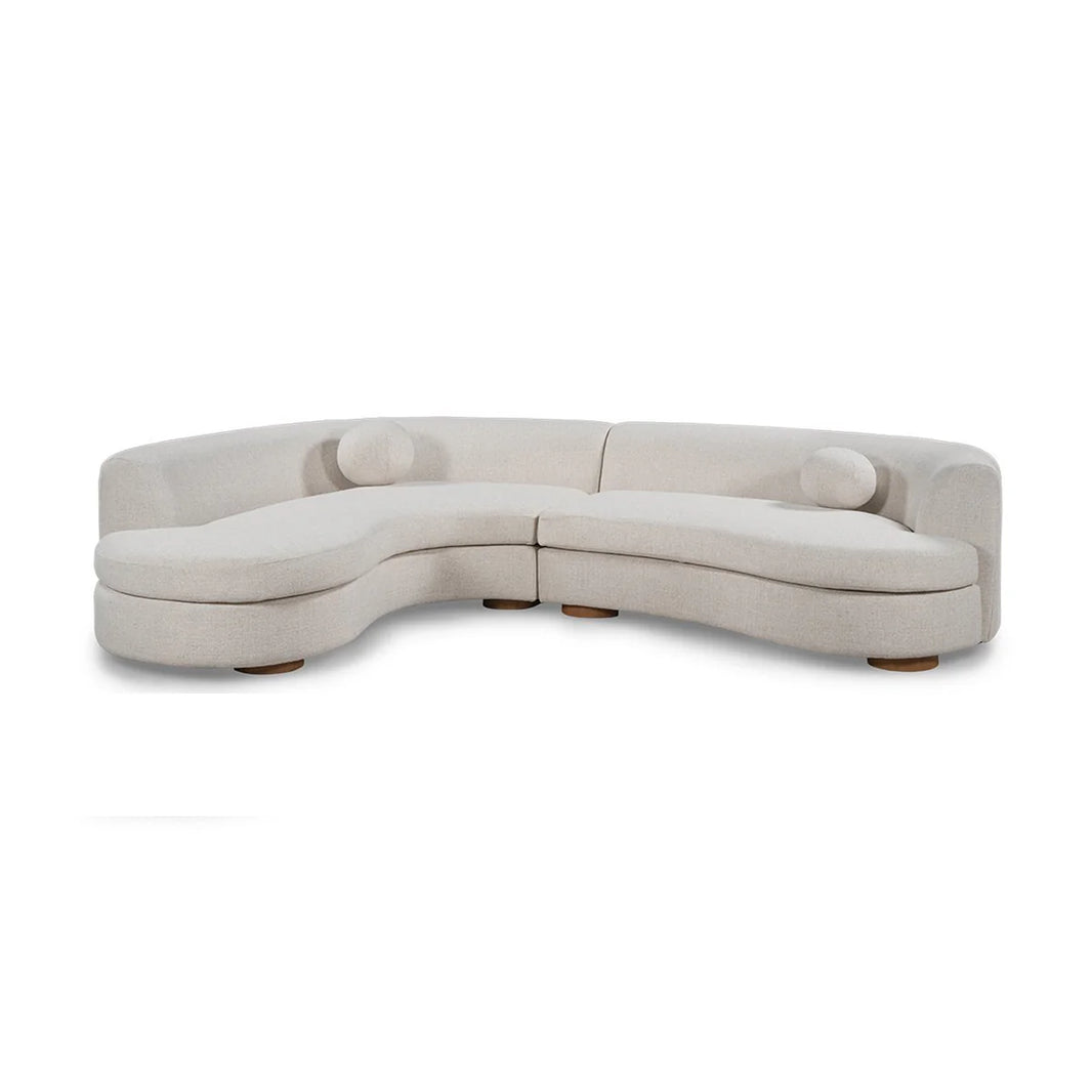 The Curved Upholstered Sectional - Ivory features a modern, minimalist design with smooth white fabric, two matching cylindrical cushions, and low wooden legs—an elegant centerpiece for any living room.