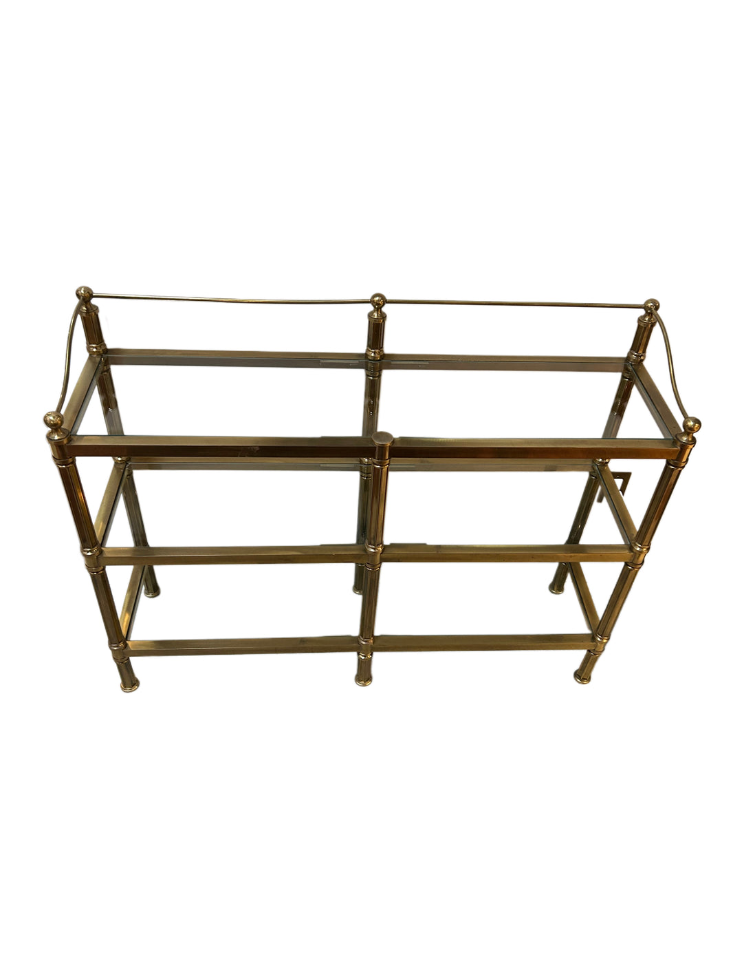 The Vintage Brass & Glass Console is a rectangular shelving unit with a double-shelf design, gold-tone metal frame, and glass surfaces. It measures 52"W x 15"D x 39"H and features four legs with decorative corner finials.