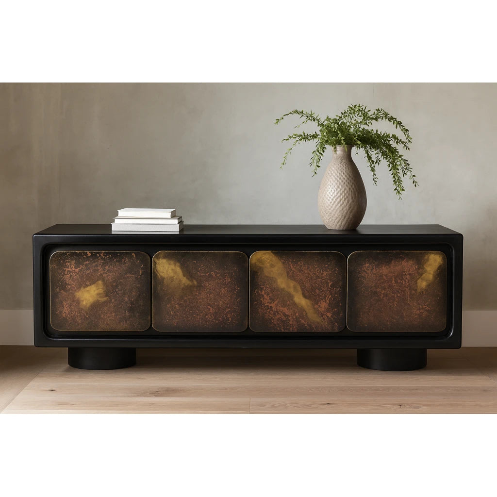 The Mazzy 4 Door Sideboard, with its sleek satin black frame and four abstract multi-color doors, is styled with a white vase filled with green foliage and a small stack of white books on top, set against a neutral wall on a light wood floor.