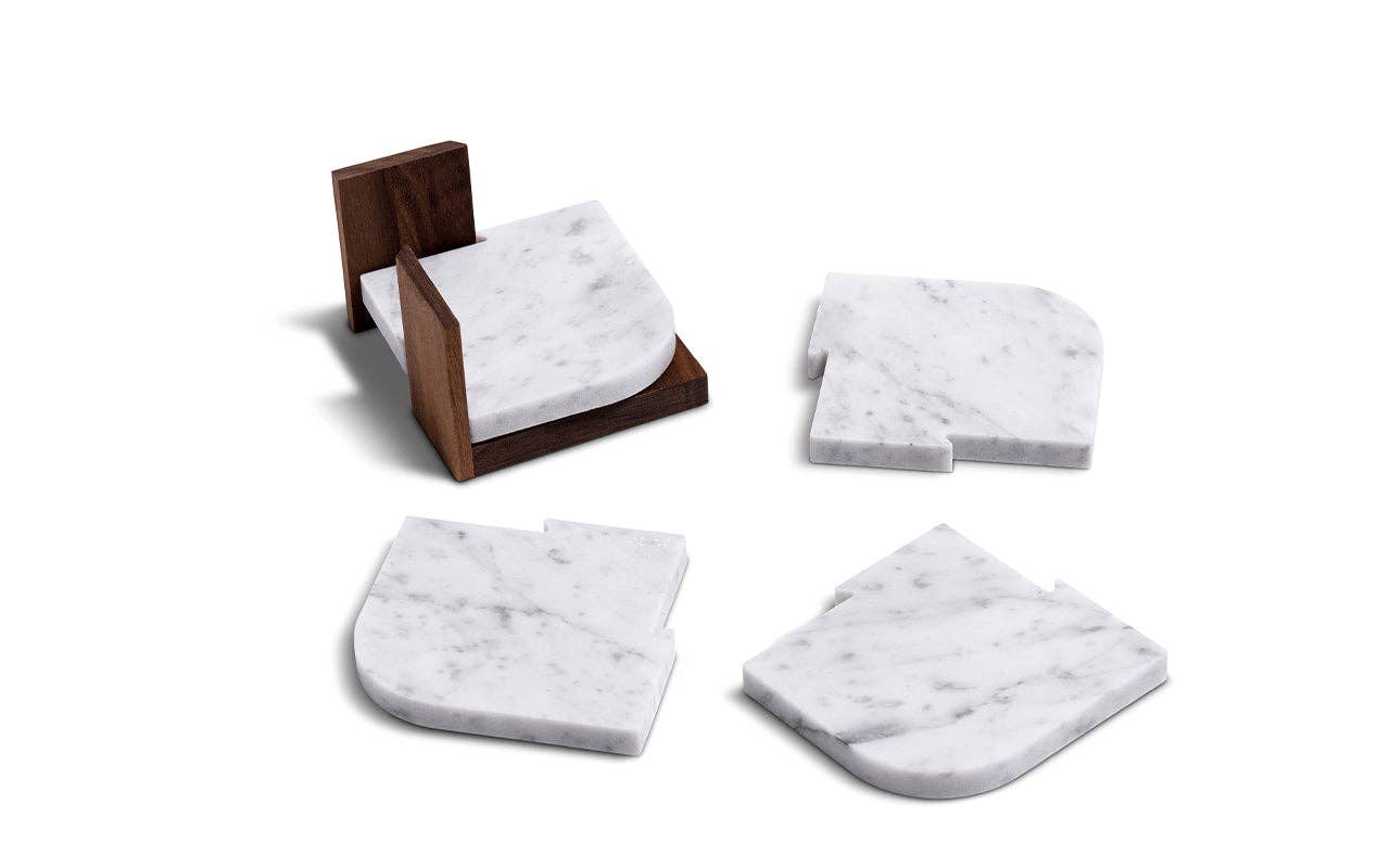 The Marble Coasters + Trivet set includes four white marble coasters with rounded edges—one stacked in a walnut stand, three arranged separately—for an elegant touch to your home.