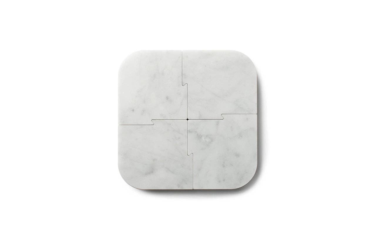 The Marble Coasters + Trivet set features four interlocking, square white marble pieces with rounded corners, arranged neatly together on a white background.