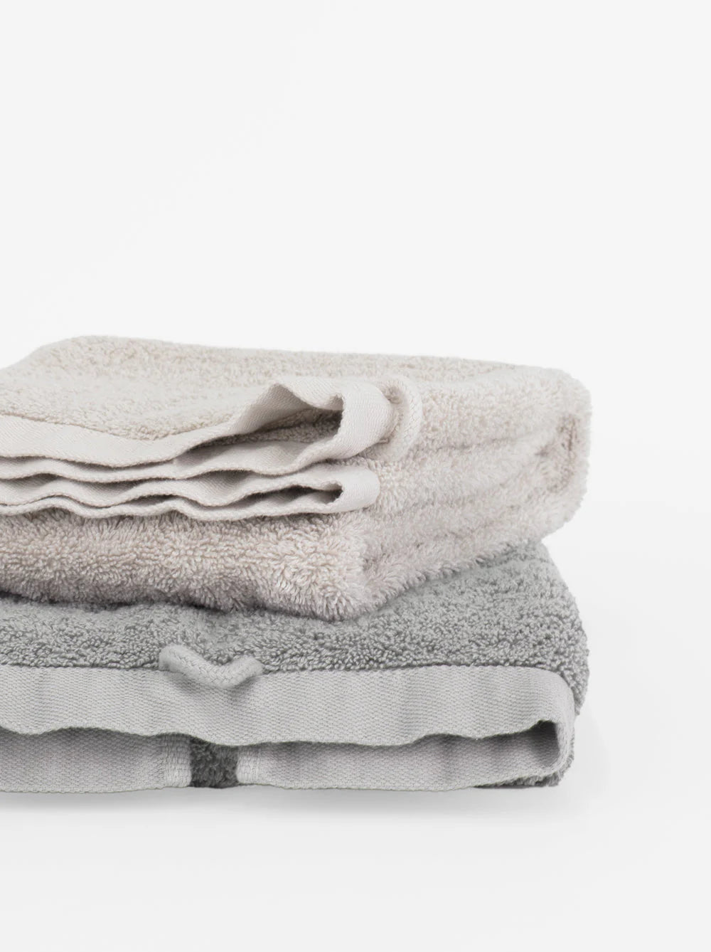 A neatly folded Riviera Cotton Wash Towel in coal rests on a white background. Crafted from soft cotton with non-toxic dyes, it’s gentle on your skin.