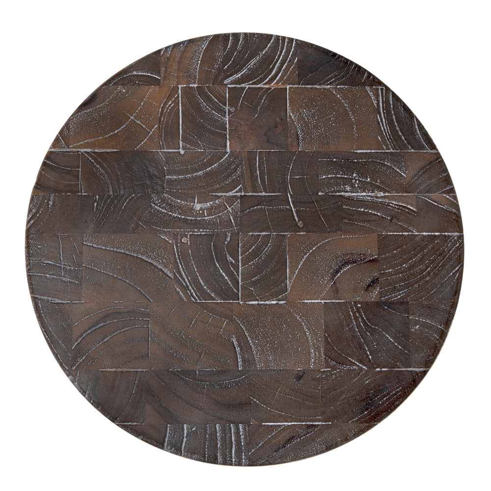 The Kongo Side Table features a round wooden tabletop with a patchwork of dark brown segments, showcasing curved and straight grain lines plus lighter streaks for an abstract, textured look.