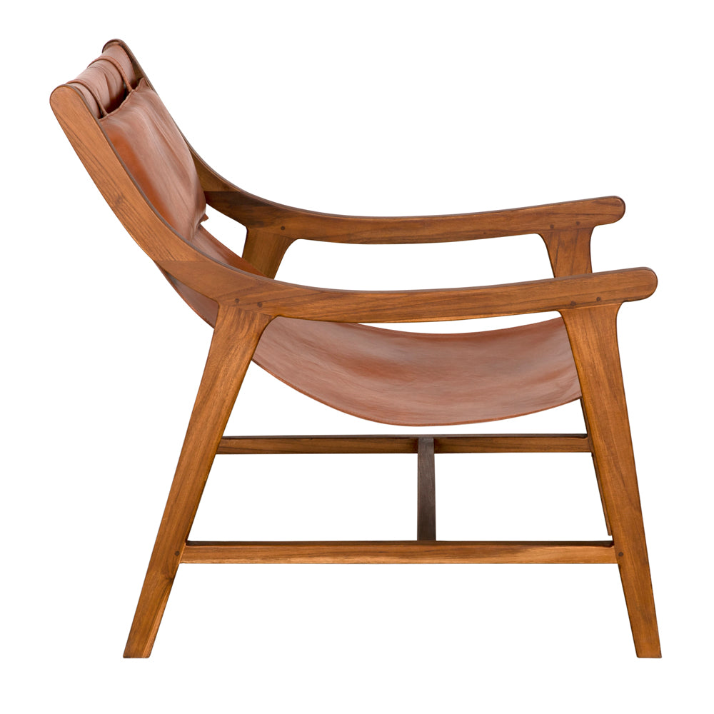 Side view of the Gilberto Chair, showcasing its teak frame and tan leather sling seat and backrest, photographed against a white background.
