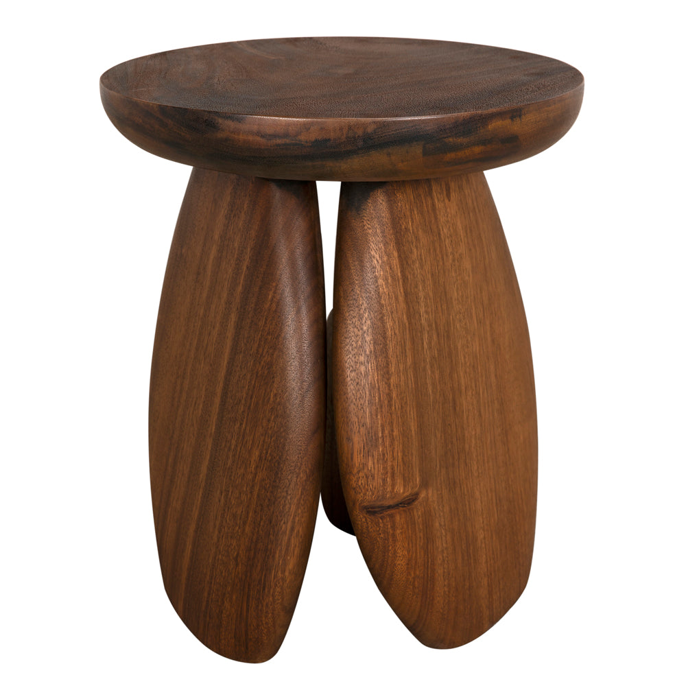The Boko Side Table is a round, solid wood piece crafted from dark teak with a natural finish, featuring three sculpted legs and a smooth top—ideal as a modern accent or unique side table.