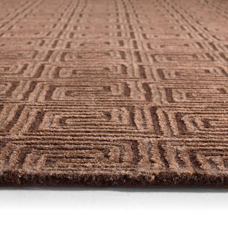 Close-up of the Geometrical Hand Tufted Rug in brown, featuring an oversized design with raised square and line patterns that highlight its texture and depth. The rug's edge is visible at the bottom.