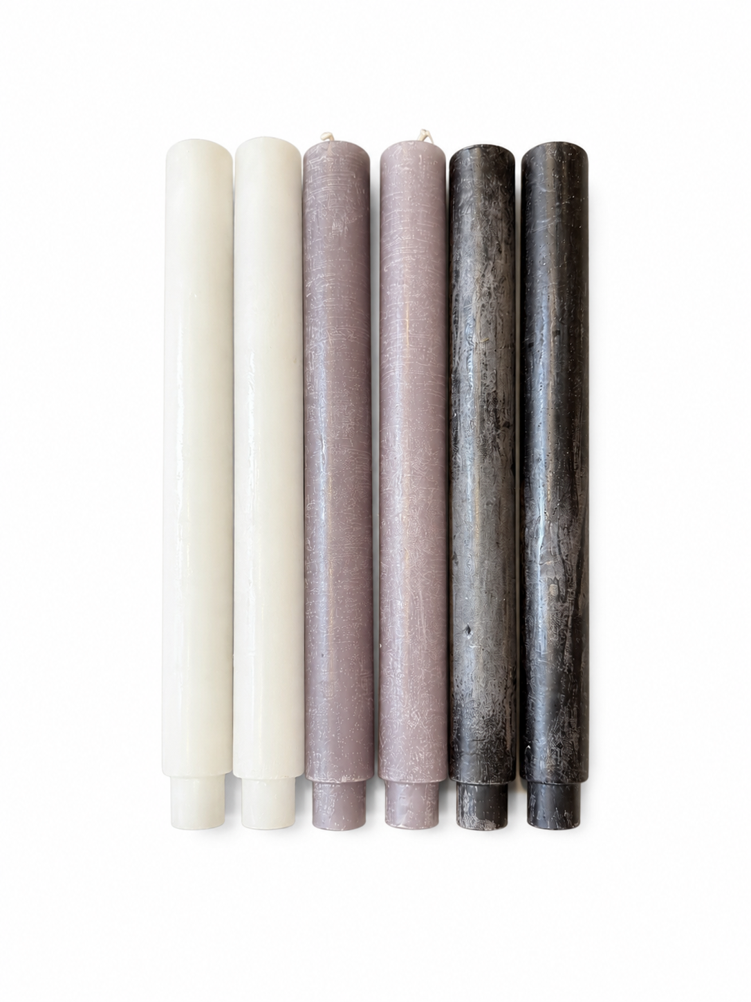 Six tall, cylindrical candlesticks from the Premium Candlestick Set - 6 Pack—each measuring 10 inches—are arranged vertically side by side on a white background; two are ivory, two are delicate lavender, and two are dark gray.