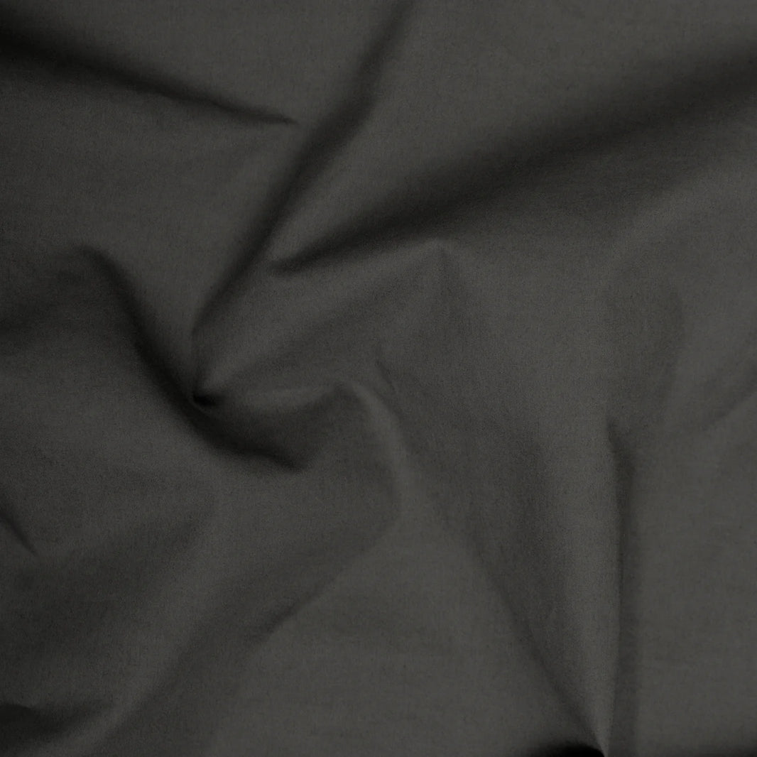 A close-up view of the XL Lumbar Pillow in charcoal linen, featuring subtly wrinkled dark grey fabric for a textured look—ideal for stylish comfort on sofas or beds.