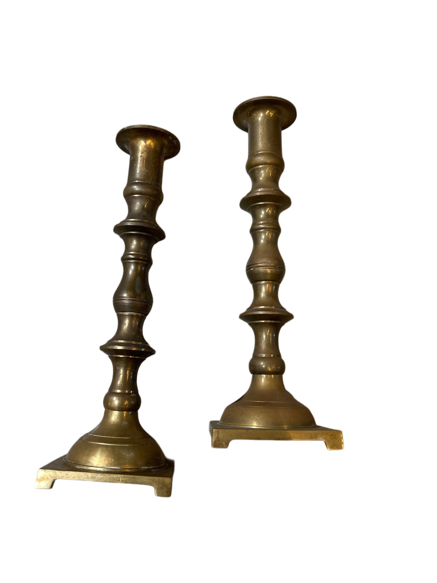 Pair of Brass Candlesticks with ornate, turned stems and square bases, shown upright on a white background.