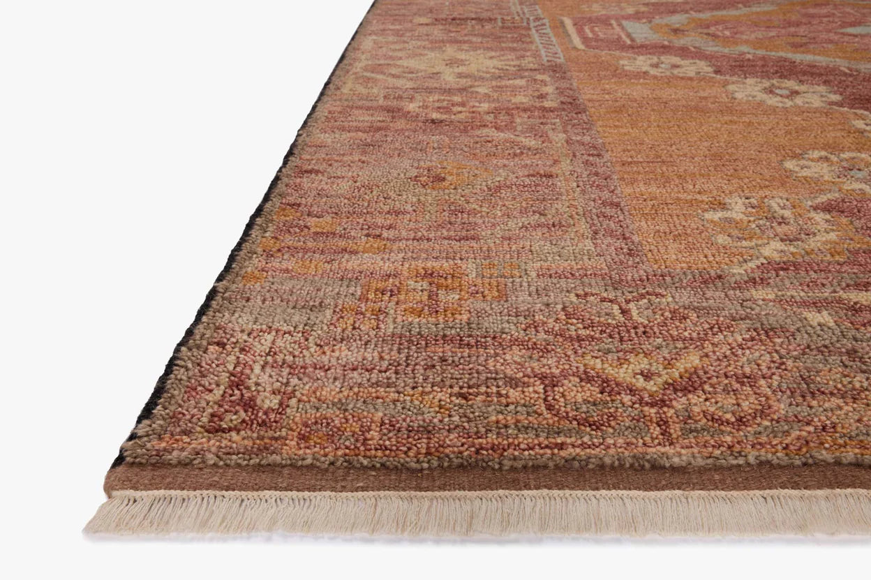 Close-up of the Spice Rug (8'-6" x 11'-6"), a vintage-style area rug made from 100% wool, featuring geometric patterns in muted red, orange, and beige with short fringe; available in various sizes.