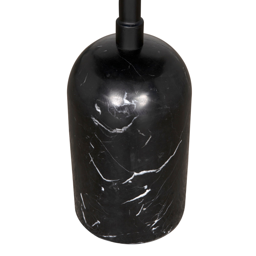 The Santosh Side Table features a black cylindrical base with a rounded top, accented by white marble-like veining and a central black rod extending upward.