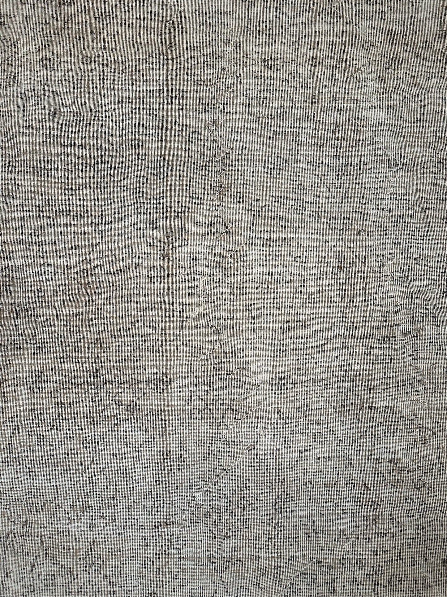 A close-up of the Reversible Vintage Rug, showing its textured surface with a grid-like pattern, faint dark lines, and subtle abstract designs reminiscent of weathered fabric.