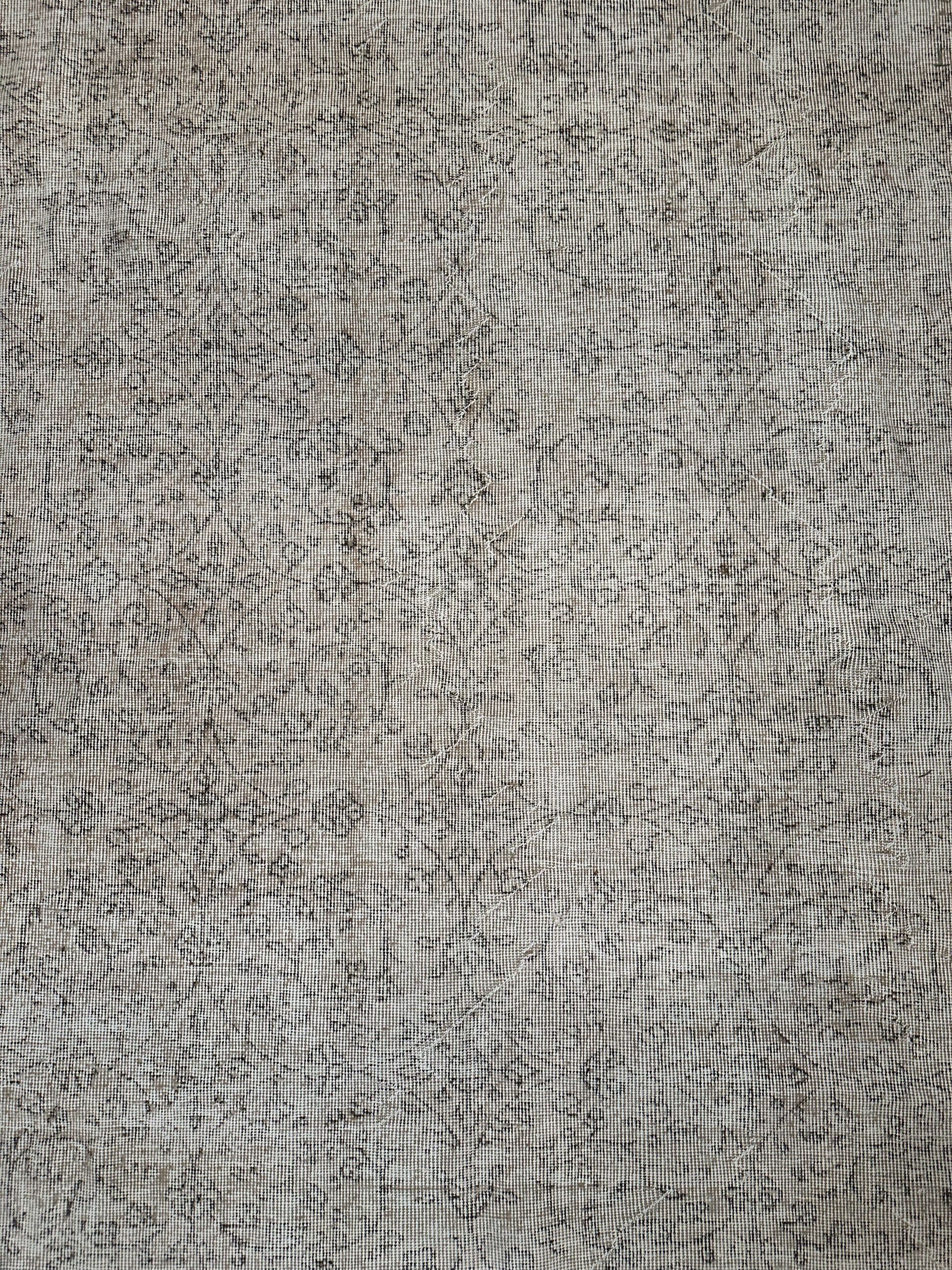 A close-up of the Reversible Vintage Rug, showing its textured surface with a grid-like pattern, faint dark lines, and subtle abstract designs reminiscent of weathered fabric.