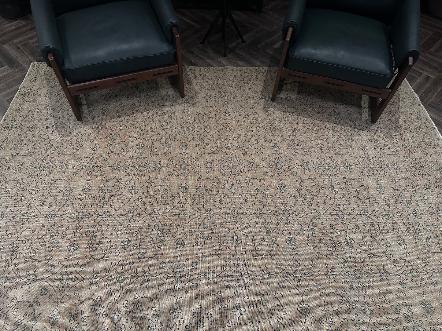 Two dark green armchairs with wooden frames sit on a Reversible Vintage Rug in beige and gray tones, atop a dark wood floor.