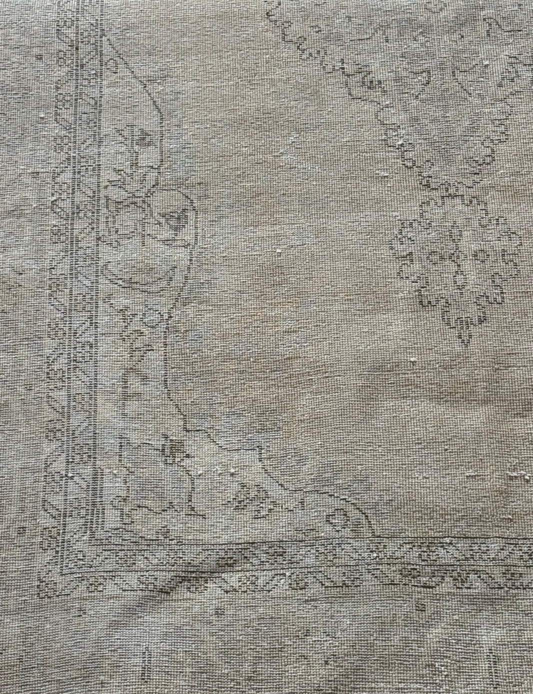 7' x 11' Dark Beige Vintage Rug featuring a faded, vintage look with a dark beige background and subtle, worn-out floral and geometric border patterns in soft gray tones—an ideal statement piece for spacious interiors.