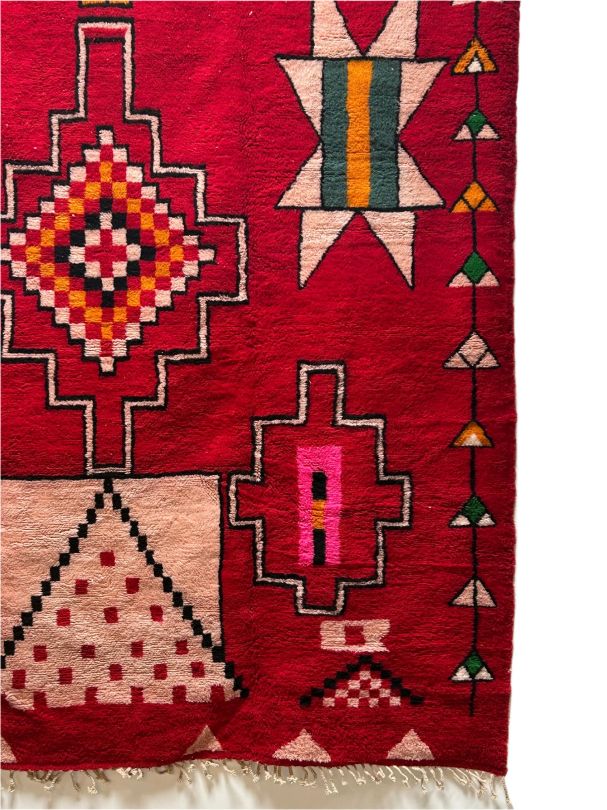 A section of the 10'x14' Colorful Vintage Moroccan Area Rug shows red geometric patterns in pink, yellow, black, and green—diamonds, triangles, zigzags, and fringe. Ideal for bringing vibrant style to your garden shed or outdoor storage space.