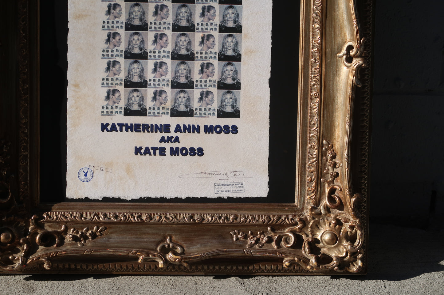 The Kate Moss Print - Vintage Art Deco Frame features repeated black-and-white portraits of the supermodel with "KATHERINE ANN MOSS AKA KATE MOSS" and official stamps/signatures, set in a partially visible ornate gold frame (30"x34").