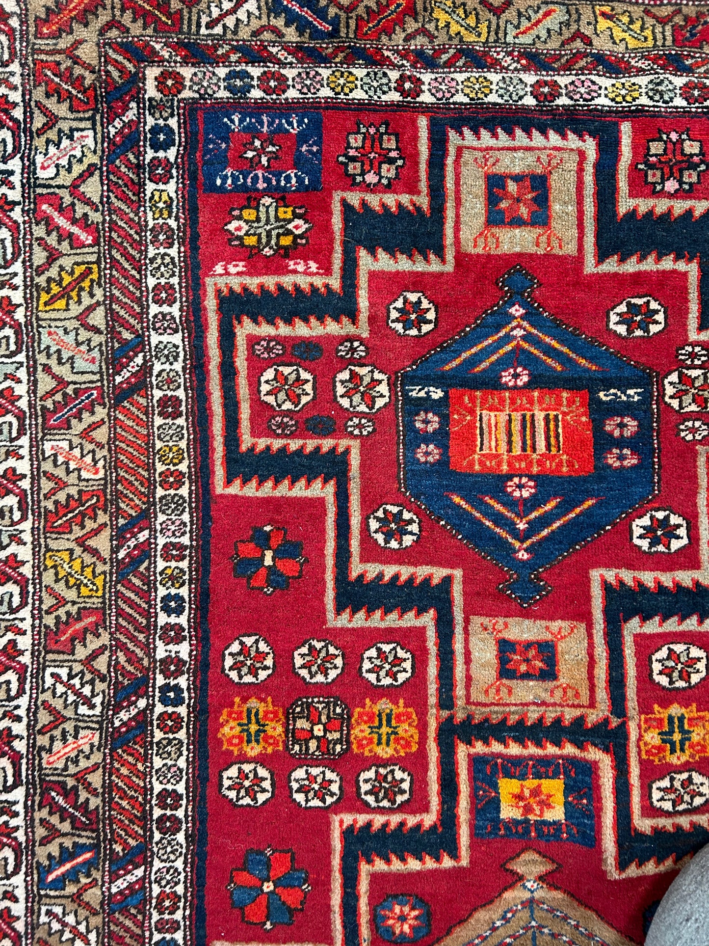 Vintage Aztec Rug featuring unique geometric shapes and floral motifs with decorative borders in vibrant red, blue, yellow, and white. Detailed traditional weaving is visible. Size: 50x83.