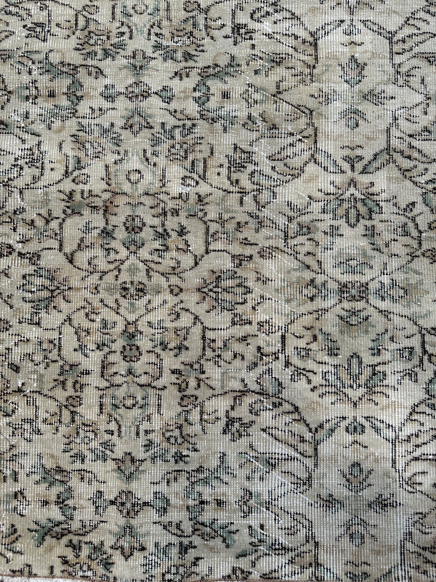 A close-up of the Vintage Turkish Rug 4x7 showcases its beige and green pattern with a detailed, symmetrical floral design, geometric accents, fine texture, and subtle color variations.