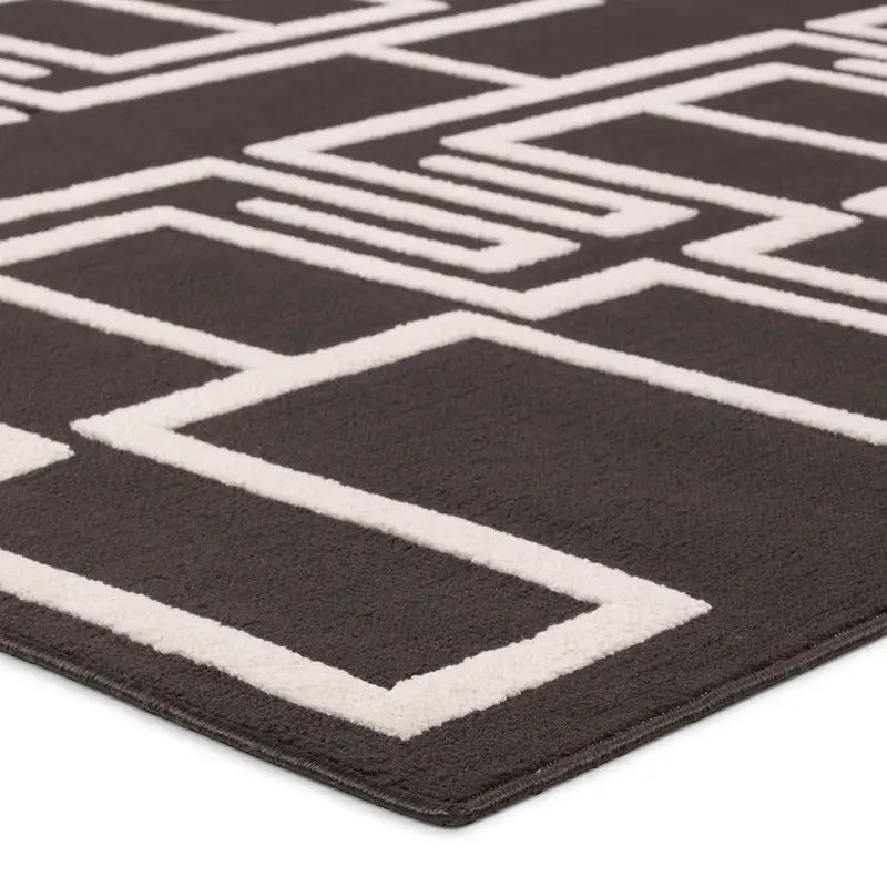 Close-up of the Geometric Outdoor Rug in dark gray, displaying a modern white pattern of interconnected rectangles and lines. The 5'3" rug has a soft, textured surface for stylish outdoor spaces.