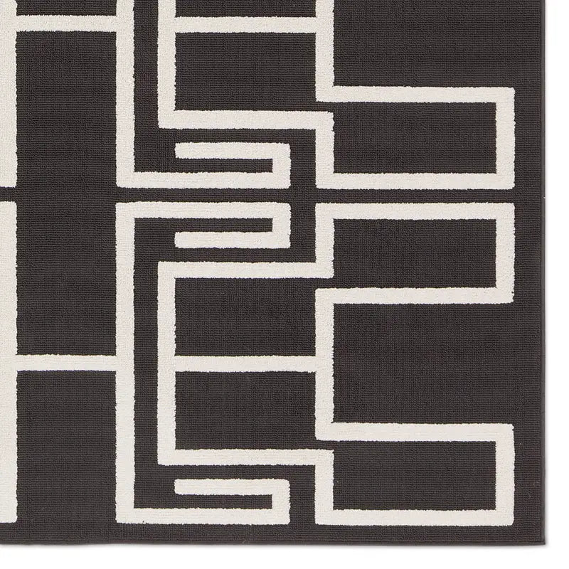 The Geometric Outdoor Rug is a black area rug featuring a bold, symmetrical white maze pattern with straight lines and right angles.