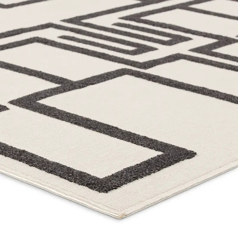 A close-up of the Geometric Outdoor Rug shows its cream surface accented by a striking black maze-inspired pattern.