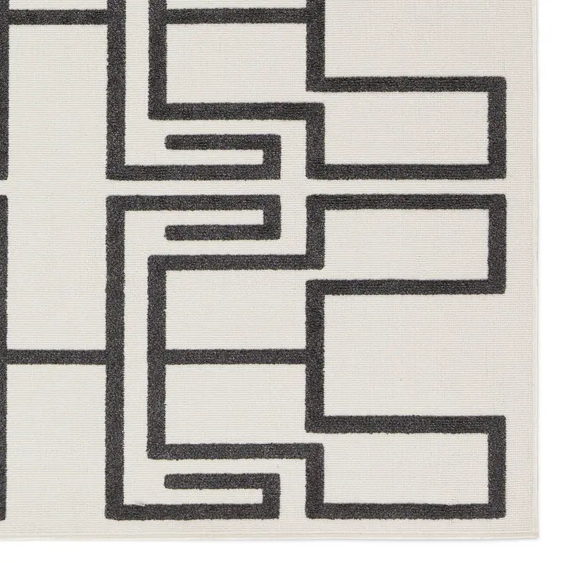 The Geometric Outdoor Rug features a white background with a bold black maze-like pattern of sharp angles and parallel lines, creating a modern, abstract statement piece for any space.