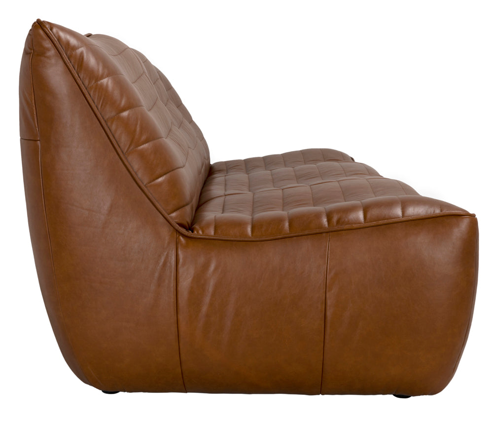 Side view of the McCLAIN 3 SEATER in Roche Tan Leather, a modern, low-profile sofa with tufted seat and back cushions, smooth curves, and a minimalist design.