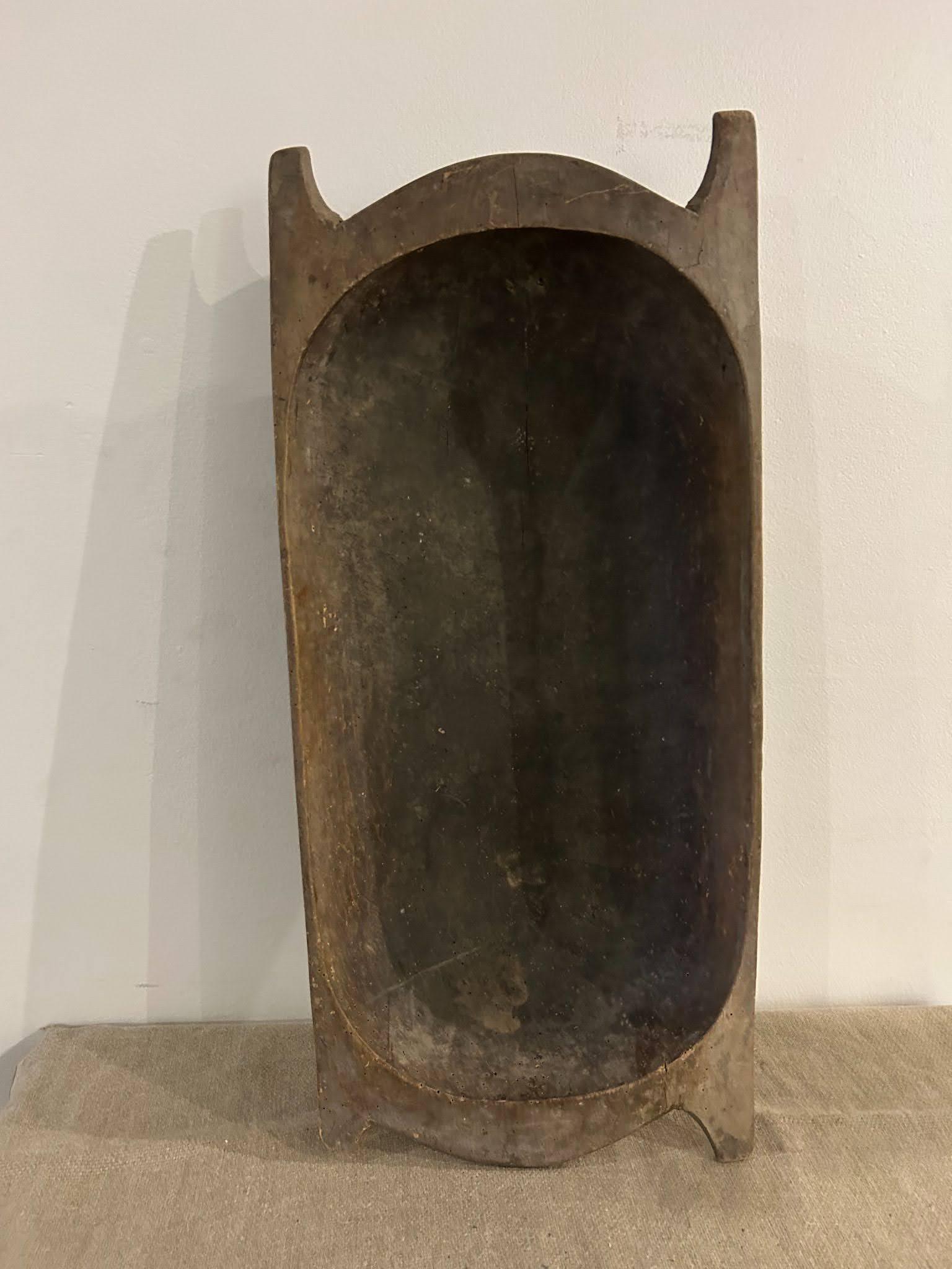 The Large Dark Display Bowl is a big, oval wooden bowl with tall sides and end handles—shown upright on a fabric surface—ideal for repurposing as a rustic 33-inch dog bed or unique large pet bed.