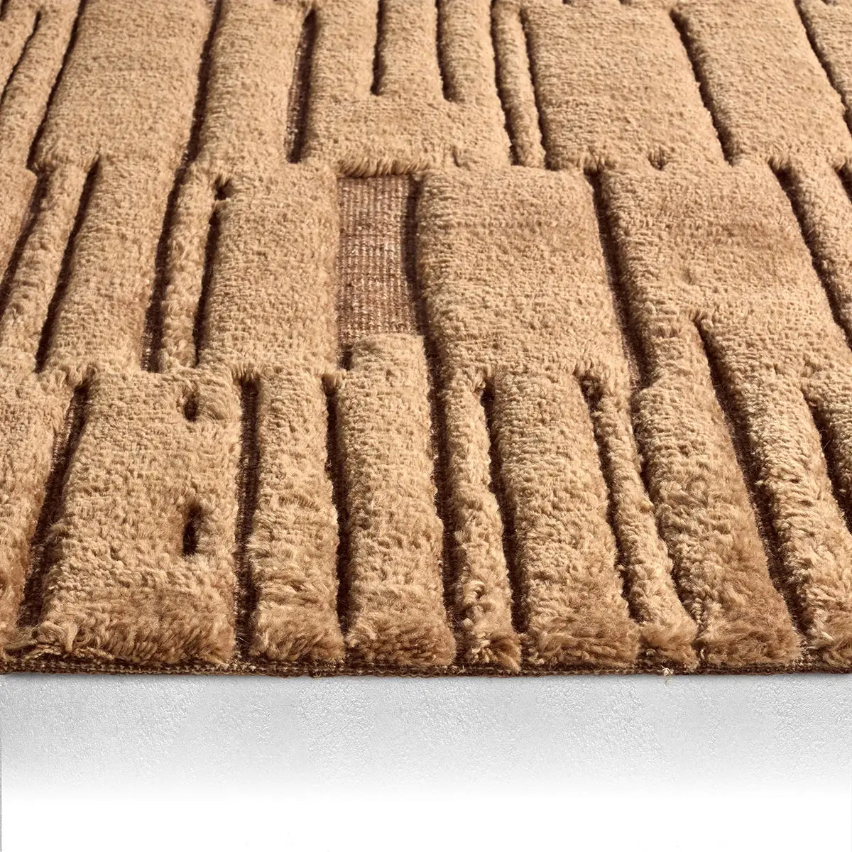 Close-up of the Abstract Geometric Rug in tan, sized 8x10, crafted from plush New Zealand wool with raised rectangular and linear patterns on a white surface.