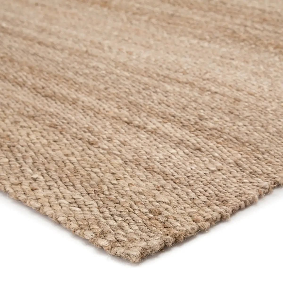 A close-up of the Natural Jute Rug - 8 x 10 displays its light beige, handwoven texture and tightly braided, slightly raised edges against a white background.