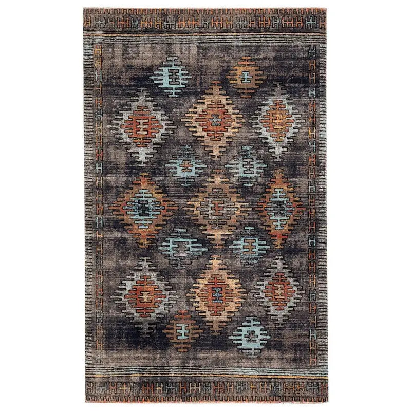 The Bohemian Vintage Rug, sized 7'6"x9'6", showcases a tribal-inspired geometric pattern in blue, orange, beige, and brown on a dark background with a decorative border. Custom sizes available.