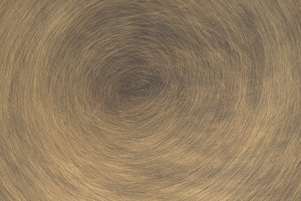 The Chandelier Two Tiered Metal with Aged Brass Finish features a circular, brushed texture that radiates from the center, creating a spiral effect. Warm lighting highlights the aged brass's reflective quality for an artisan-crafted look.