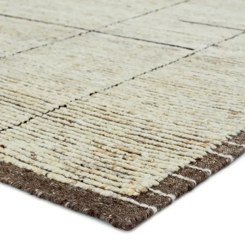 Close-up of the Textural Natural Brown-Cream Rug, showcasing its beige woven surface with a subtle grid pattern and brown edges. The texture and stitching details enhance its handcrafted look.
