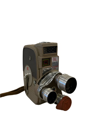 A vintage Keystone movie camera with a brown body, dual silver lenses, an Electric Eye feature, and a red button, isolated on a white background.