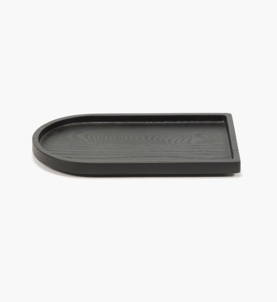 The Small Arch Black Tray, made from carbonised ash wood in black, features a flat rectangular base with one rounded end and measures 11.81"L x 7.09"W x 0.98"H, shown against a plain white background.