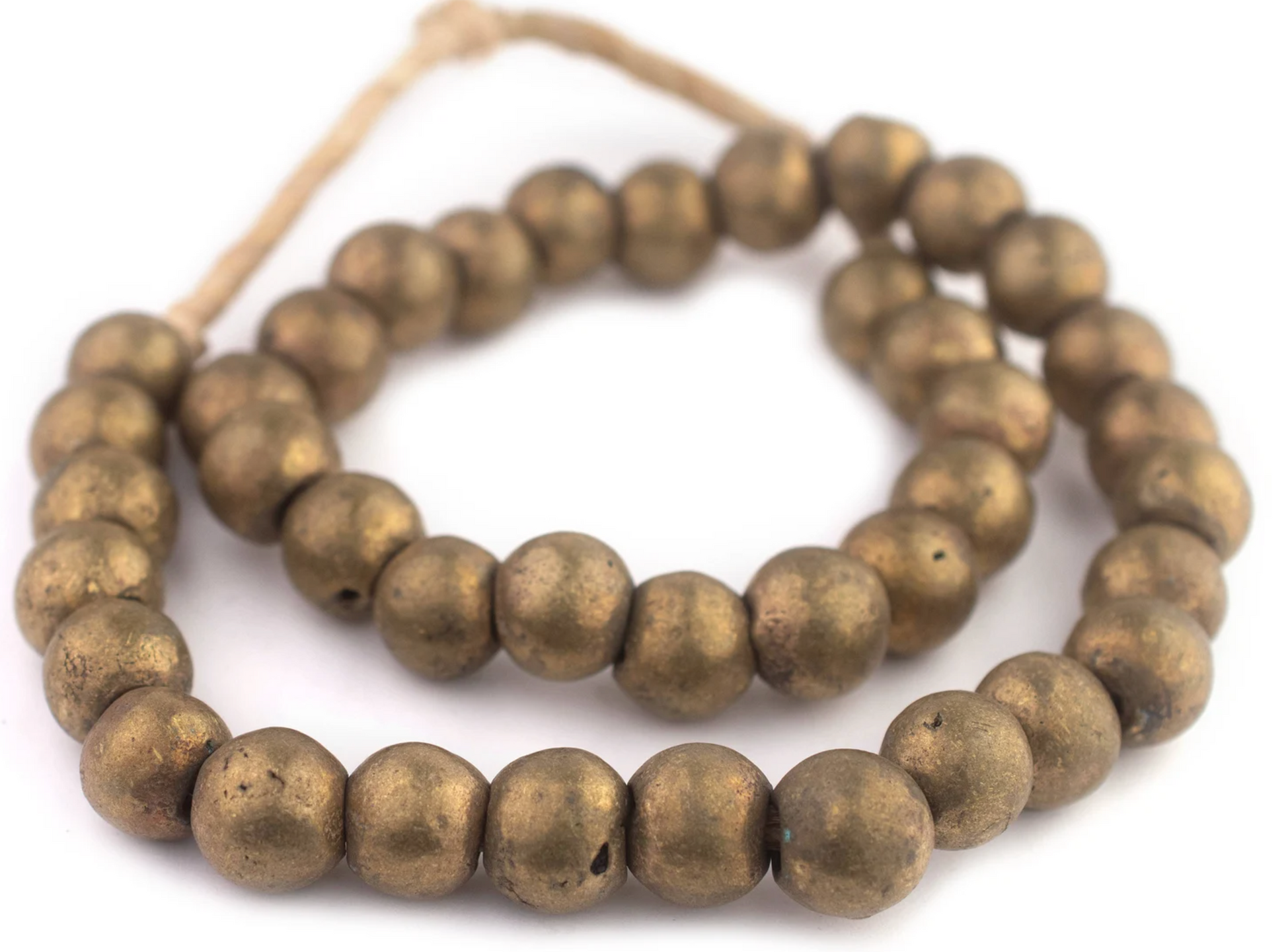 The Brass Beads feature round, metallic-looking beads with a rustic, handmade appearance, strung on twine and forming two loose loops.