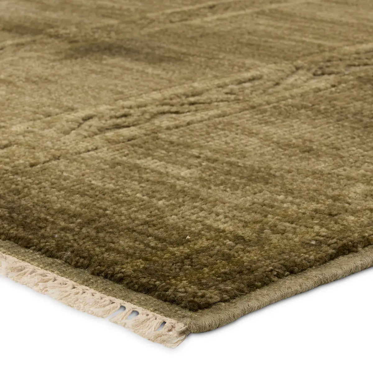 Close-up of the Green Monochrome Diamond Wool Rug (8x10), showcasing its plush, textured greenish-brown wool with subtle diamond patterns and a distinctive white fringe along the edge.