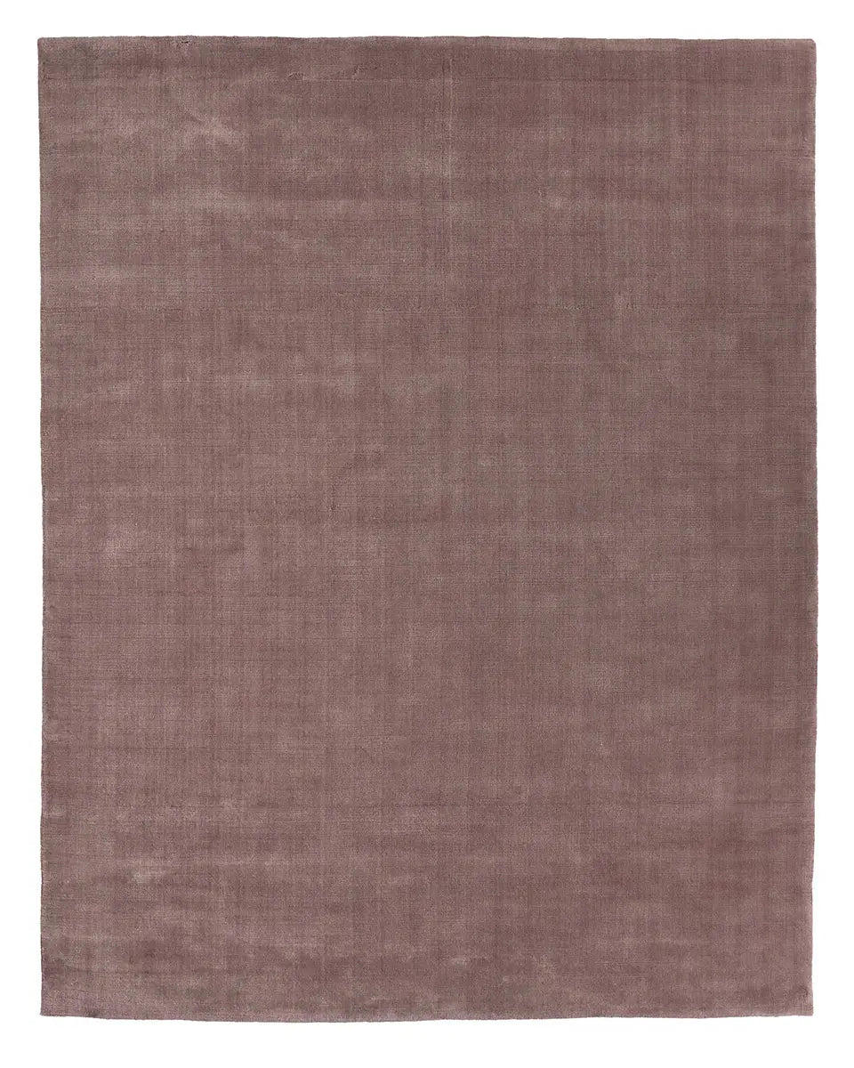 A large 8x10 Handwoven New Zealand Wool Rug, featuring a solid, muted mauve color and a smooth, uniform texture.