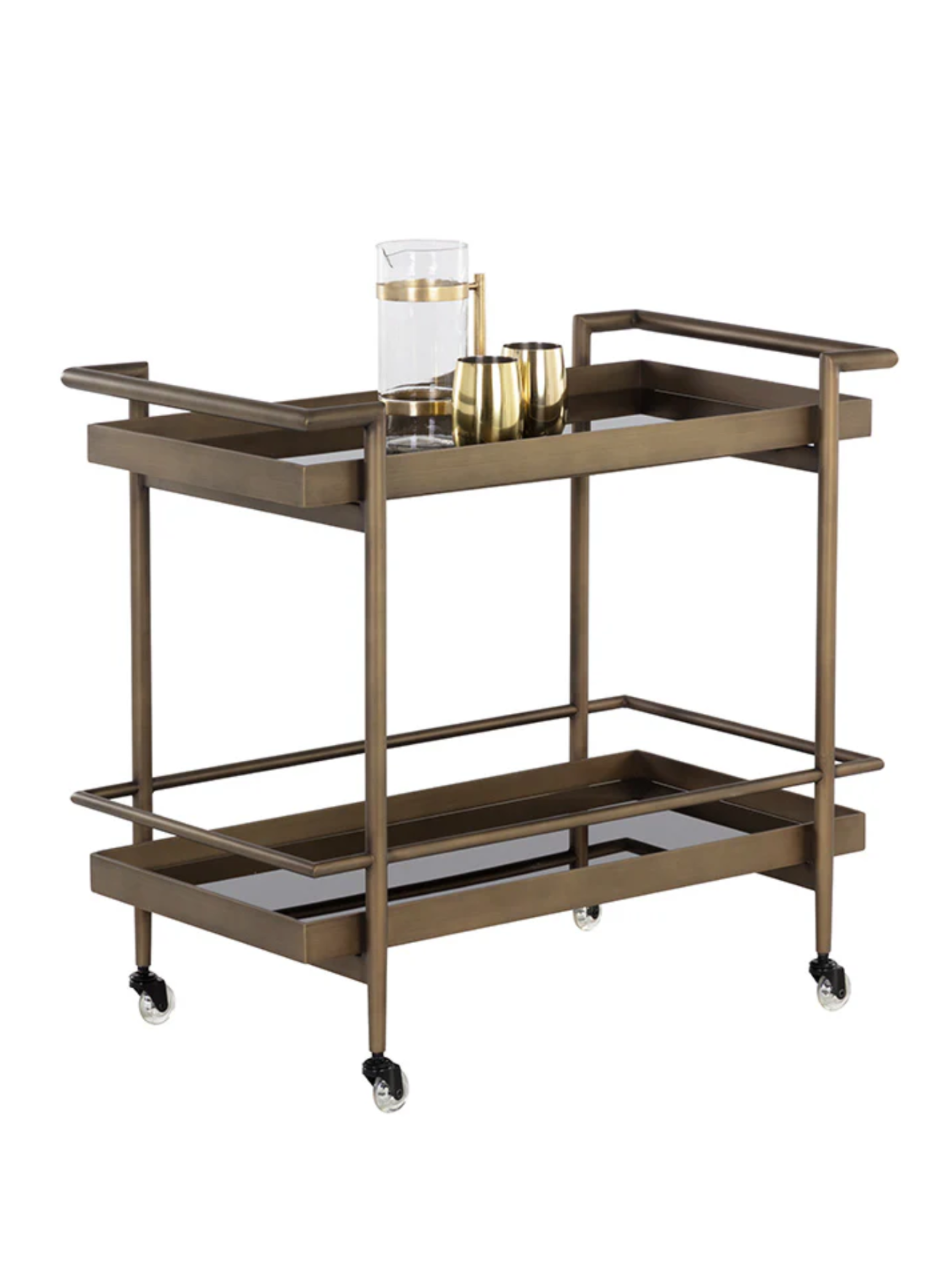 The Smoke Glass Bar Cart features two black glass tiers, four wheels, and an antique brass frame. The top shelf displays three gold drinkware pieces and a clear glass pitcher filled with water.