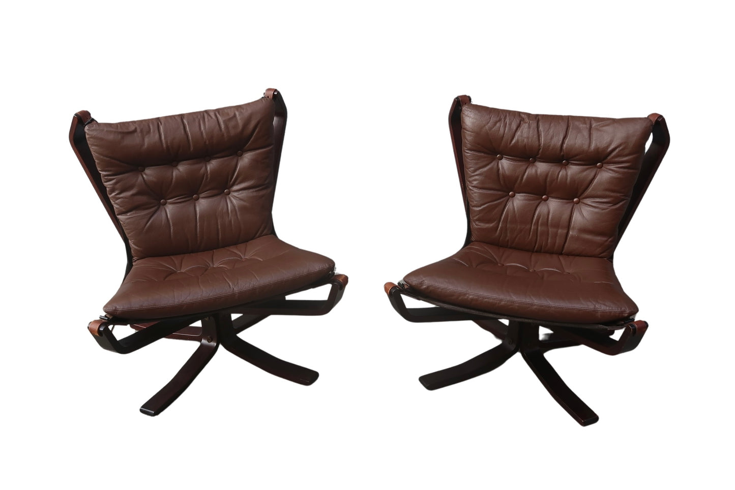 A pair of Vintage Falcon Chairs with dark brown tufted leather seats, curved wooden frames, and swivel bases are placed side by side against a white background—a classic Sigurd Ressell design.