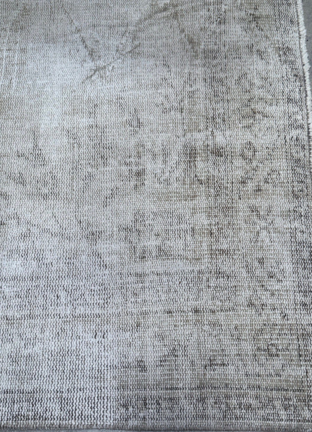 A close-up of the Vintage Cream/Grey Turkish Rug, featuring a light gray and beige woven design with a subtle, faded pattern and slightly frayed edges. This piece measures 8'8" x 5'3".