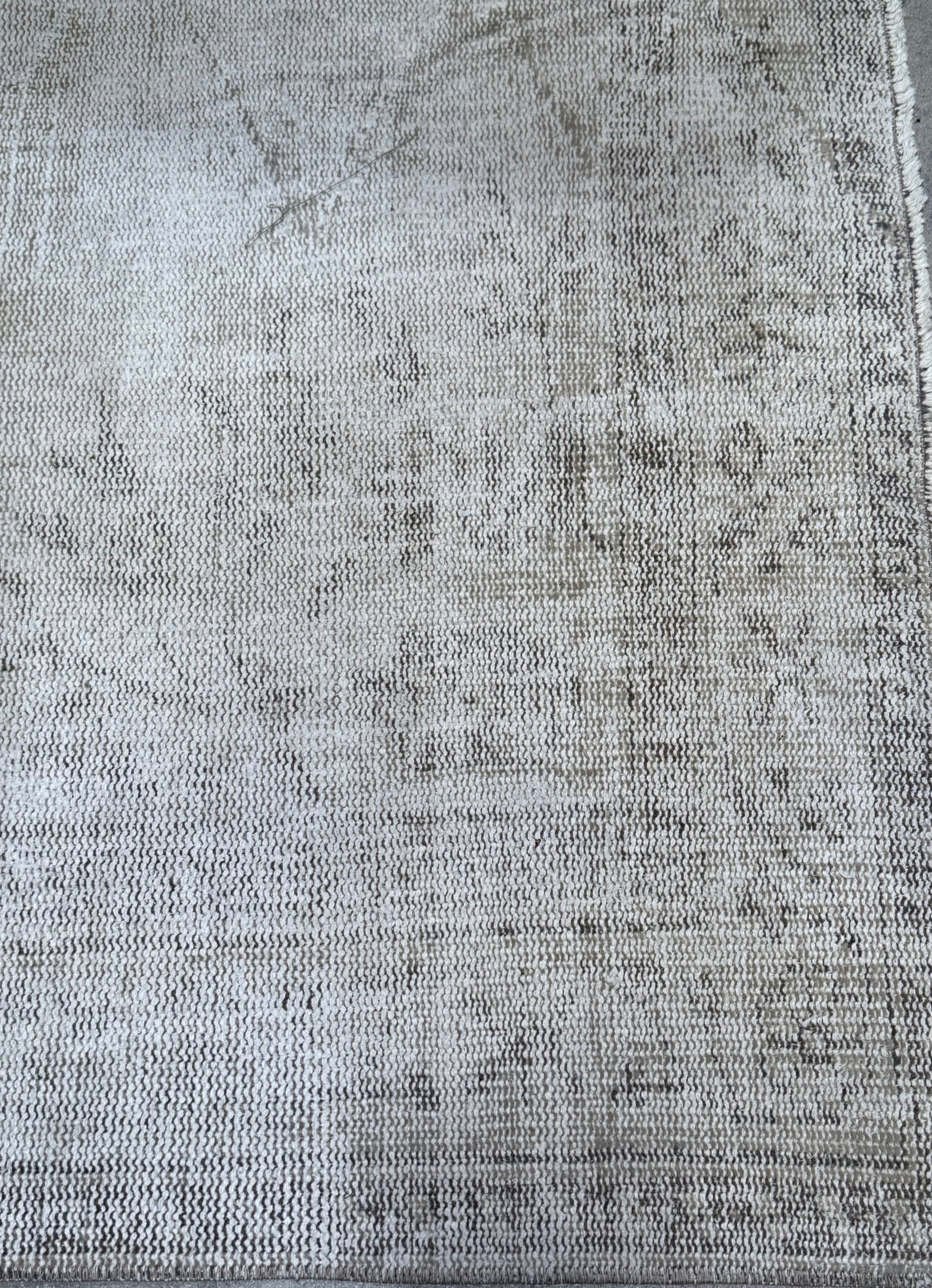 A close-up of the Vintage Cream/Grey Turkish Rug, featuring a light gray and beige woven design with a subtle, faded pattern and slightly frayed edges. This piece measures 8'8" x 5'3".