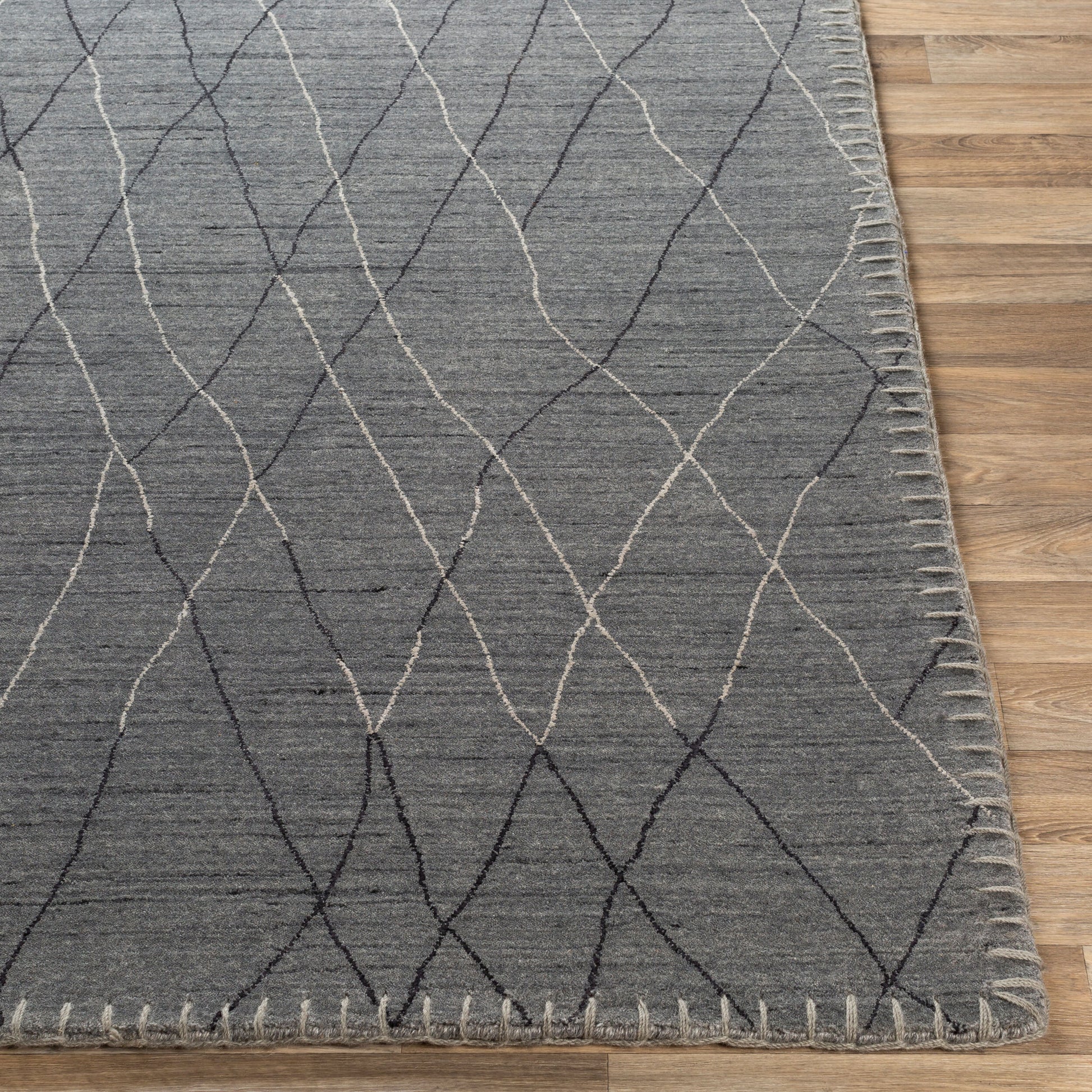 The Diamond Sketch Rug - 8 x 10 features a gray base with thin white and black crisscross lines, visible edge stitching, and is shown on a light brown wood floor. Various sizes are available, including the 8' x 10' option.