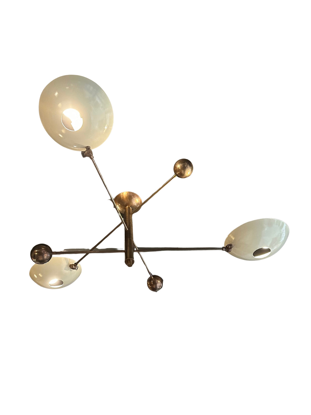 The Mid Century Brass Chandelier features three white bowl-shaped lampshades and multiple brass arms and spheres extending from a central base, creating an elegant, abstract look. Photographed against a white background.