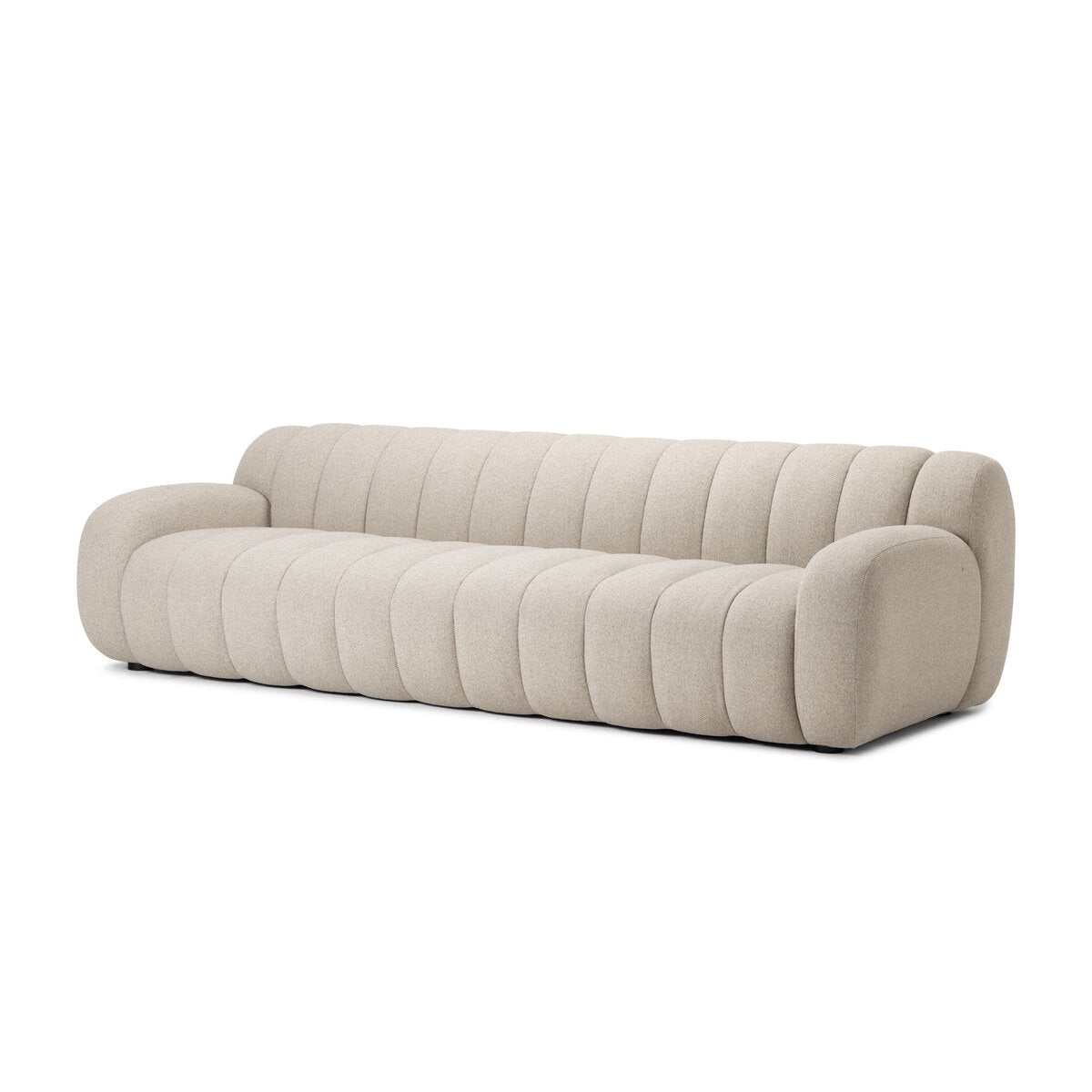 The Plush Channeled Sofa is a modern beige three-seater with rounded arms and backrest, featuring quilted wide channeling across the surface for a cloud-like appearance.