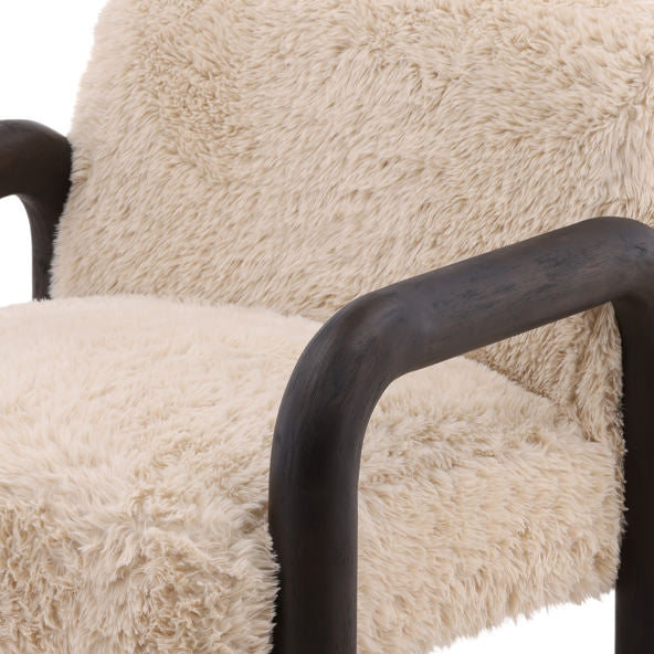 The Fur Armchair with Curved Wooden Frame features soft sand-colored fur upholstery and elegantly curved dark brown wood armrests, offering cozy comfort and inviting style for your space.