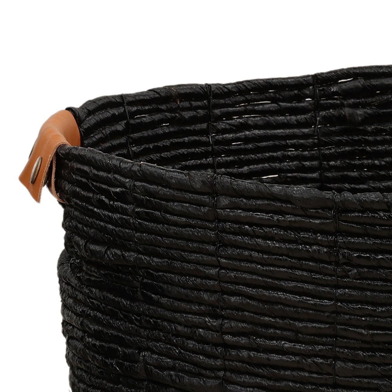 A close-up of the Leather Detail Woven Basket (Set of 3), featuring a black textured surface and a brown leather handle on the rim.